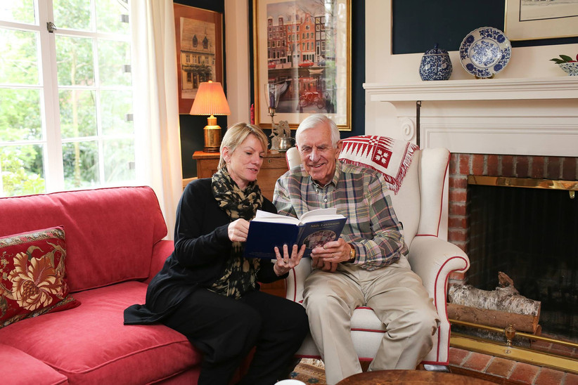 Пожилая пара читает книгу памяти в уютной гостиной