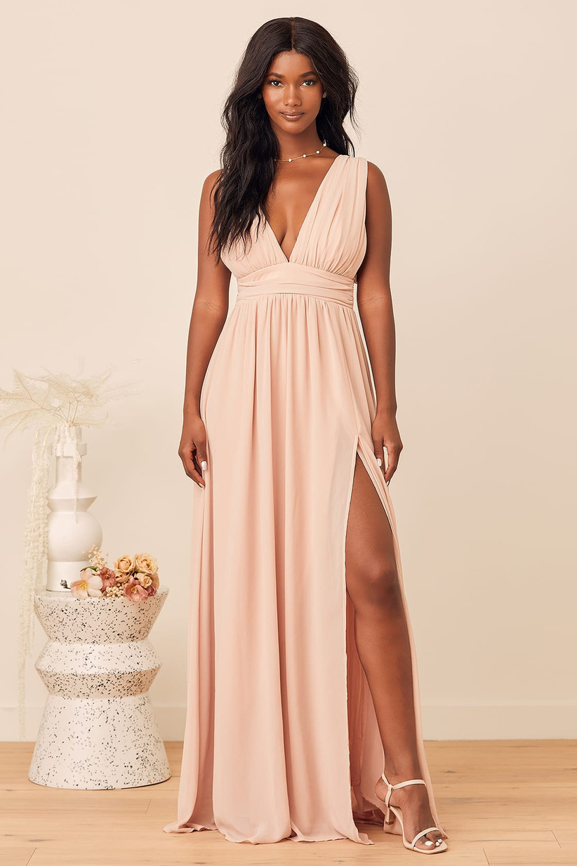 Model wearing deep V-neck pastel pink bridesmaid dress with leg slit