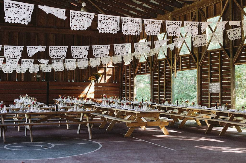 wedding reception set up with wooden picnic tables and paper garlands