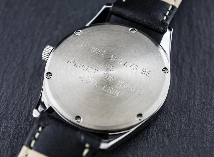 Minimalist leather-strap watch turned over to show engraved back that reads It Will Always Be Us Against the World