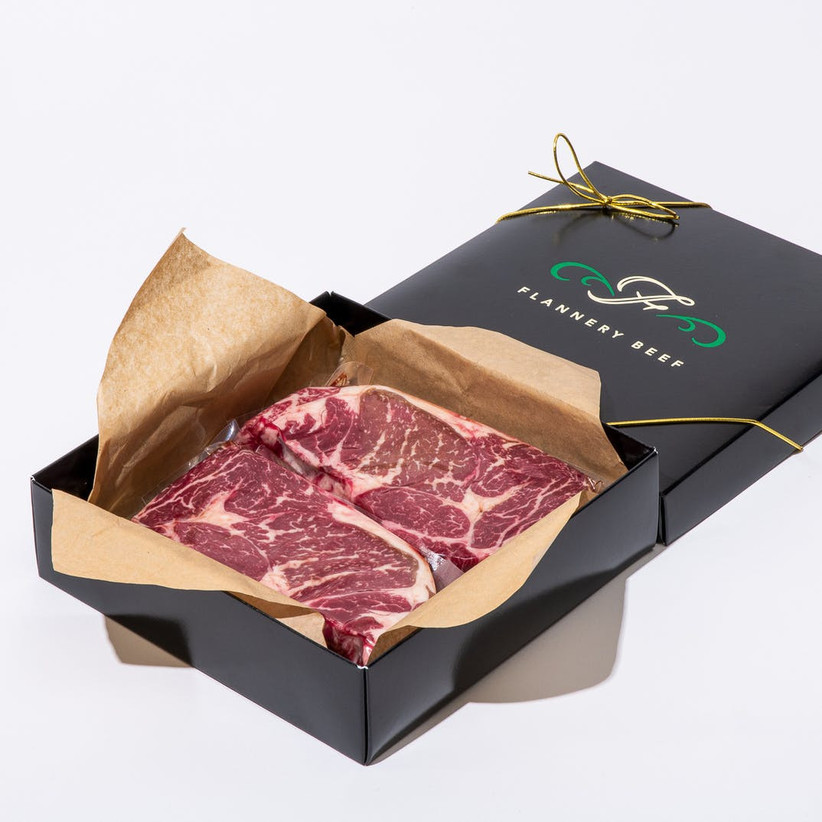 Flannery Beef black gift box with the lid off the reveal two juicy steaks