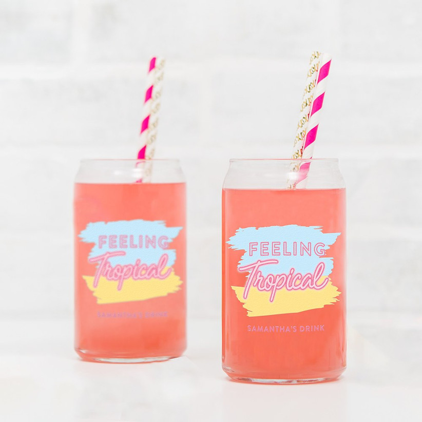 Two can-shaped drinking glasses that read Feeling Tropical personalized with names
