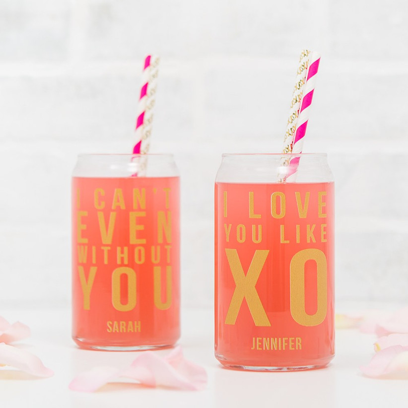 Two can-shaped cocktail glasses with colorful straws and fun slogans