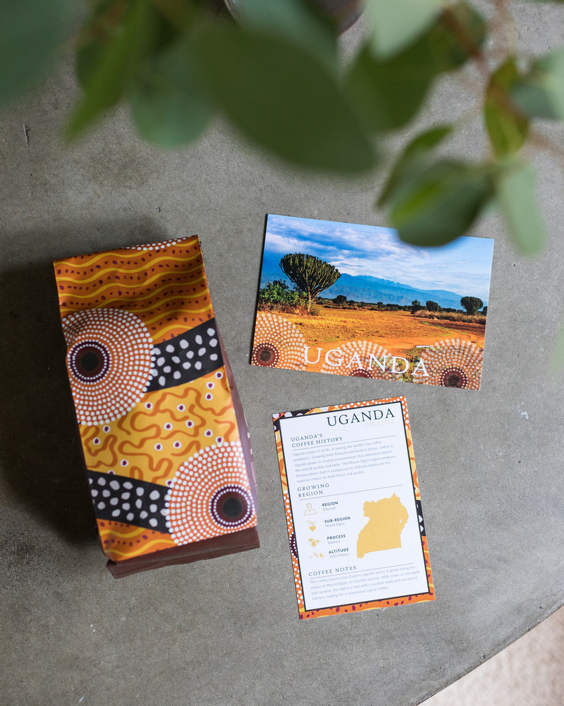 Colorful and patterned bag of coffee with Uganda postcard and informational card about Ugandan coffee