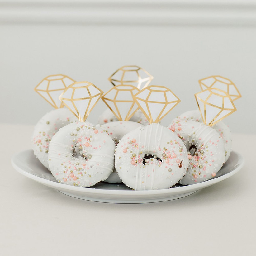 Plate of delicious donuts with white icing, pretty sprinkles, and diamond cake toppers