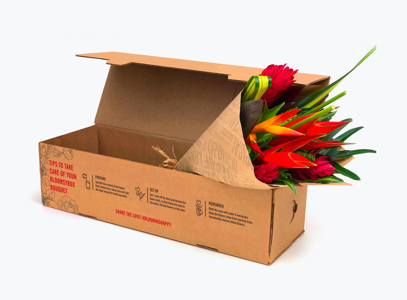 Tropical bouquet wrapped in brown paper positioned in a brown delivery box