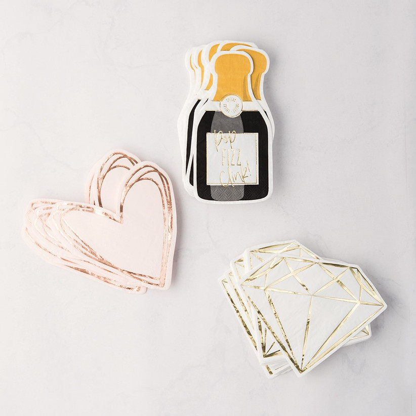 Three stacks of napkins in different designs, including hearts, diamonds, and champagne bottles