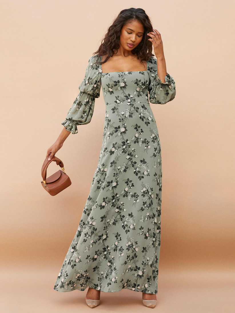 Model wearing sage green maxi with double puffed sleeves and floral print in varying shades of green