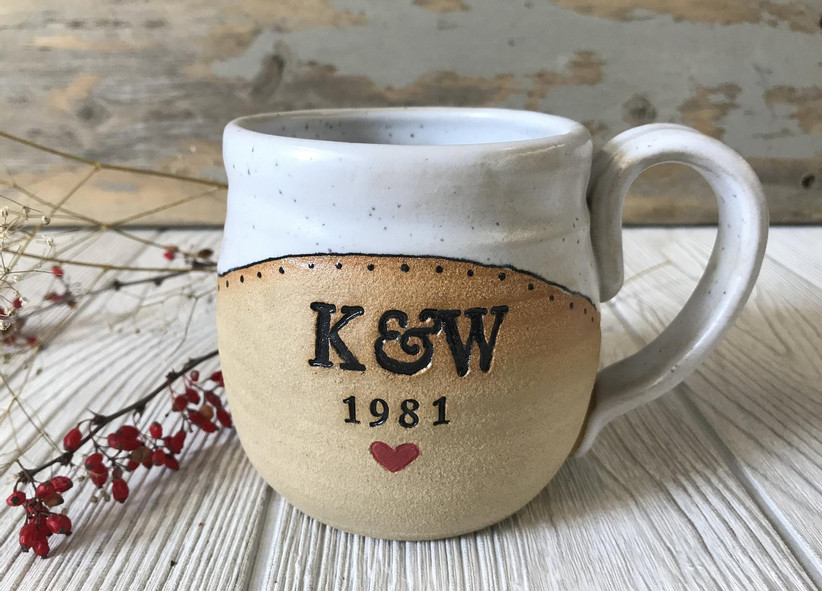Handmade white and beige pottery mug with coupe's initials in black, the year 1981, and a red heart