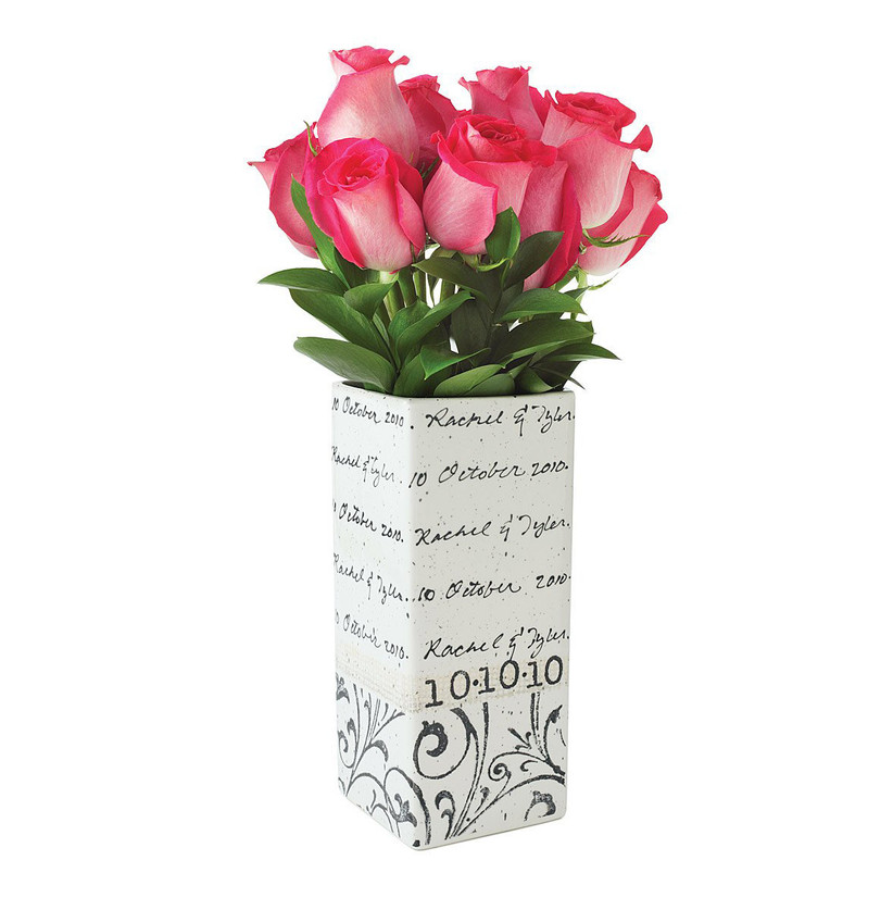 White rectangular vase with black cursive design filled with pink flowers