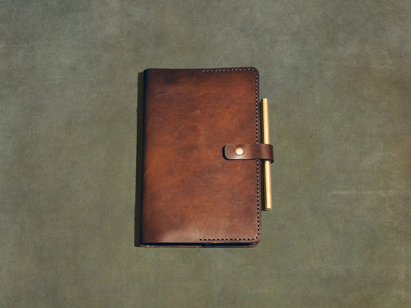 Premium brown leather journal cover with button closure and a pen