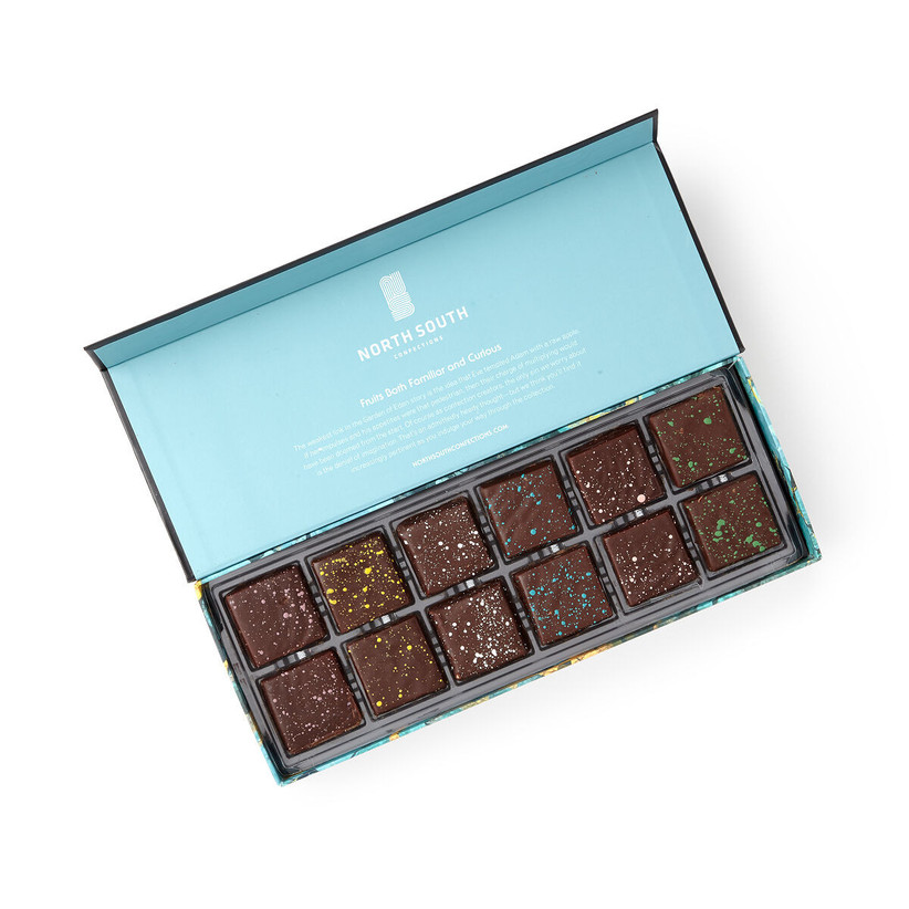Opened box of North South Confections chocolates showing 12 delicious chocolates with a unique splash of color
