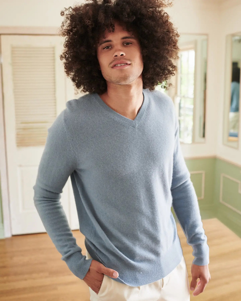 Model wearing light blue cashmere v-neck sweater with hand in his pocket