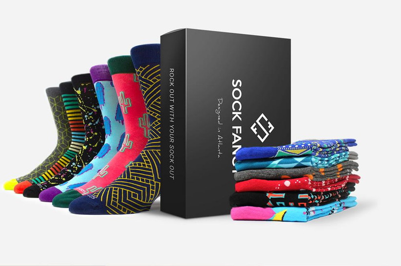 Black Sock Fancy subscription box next to stack of colorful socks and row of socks on display
