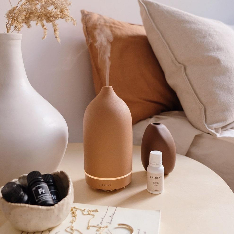 Terracotta-colored stone diffuser on table with collection of essential oils