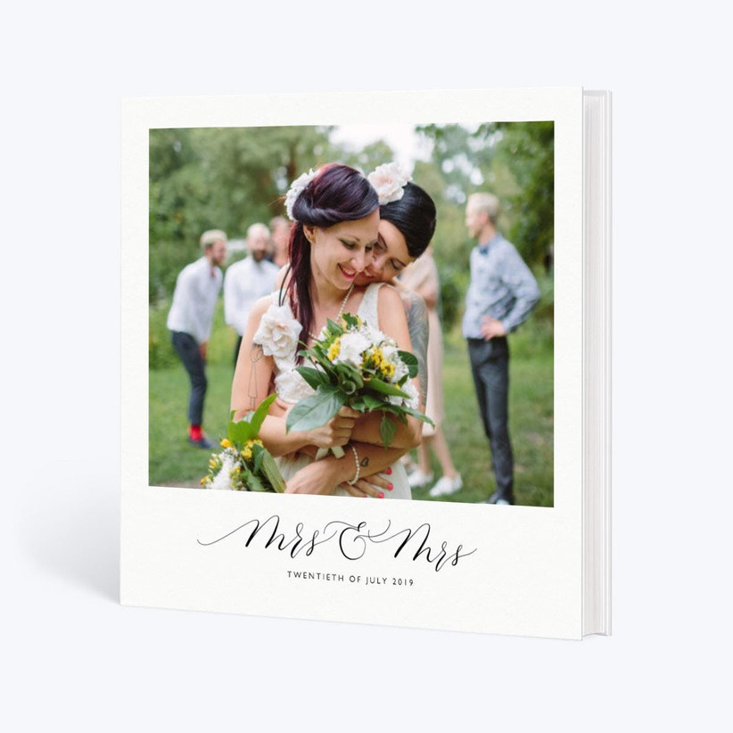 Белая свадебная фотокнига с большой фотографией двух невест на обложке с миссис и миссис и датой свадьбы, указанной ниже.