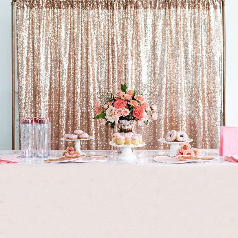 Rose gold sequin curtain backdrop set up behind an elegant dessert table