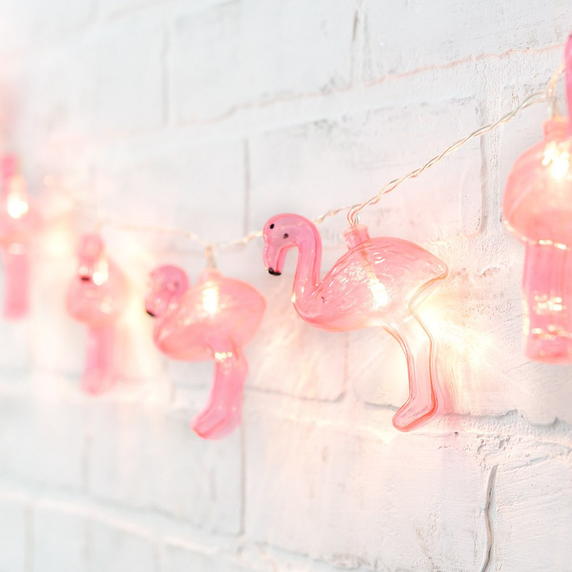 Flamingo string lights strung against white brick wall