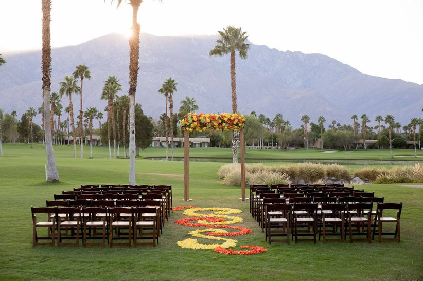 свадебная церемония на открытом воздухе на поле для гольфа на фоне гор и красочных цветочных проходов