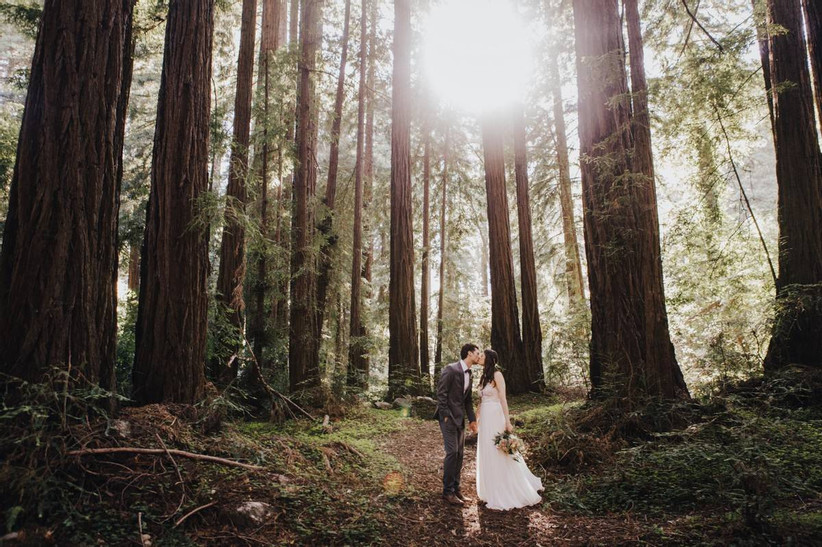 bride and groom kissing amid trees