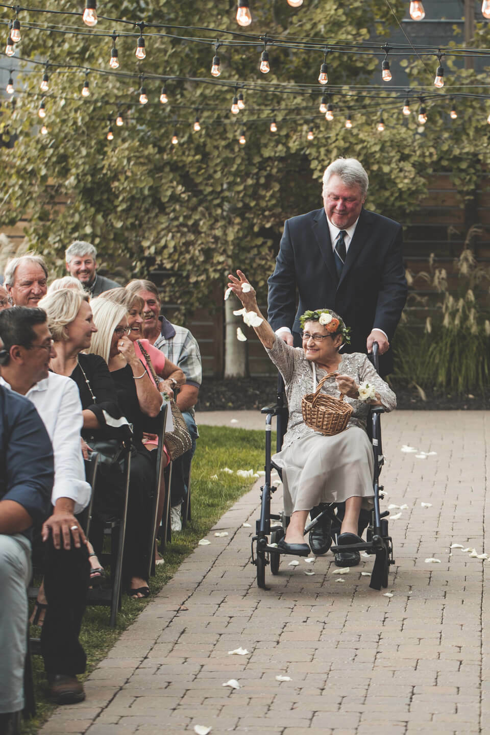 Flower grandma in floral crown sprinkles petals down the aisle from her wheelchair