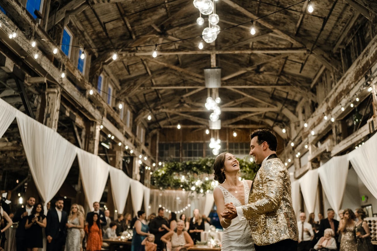Newlyweds dance at their barn reception surrounded by wedding guests | Sodo Park by Herban Feast, Seattle WA