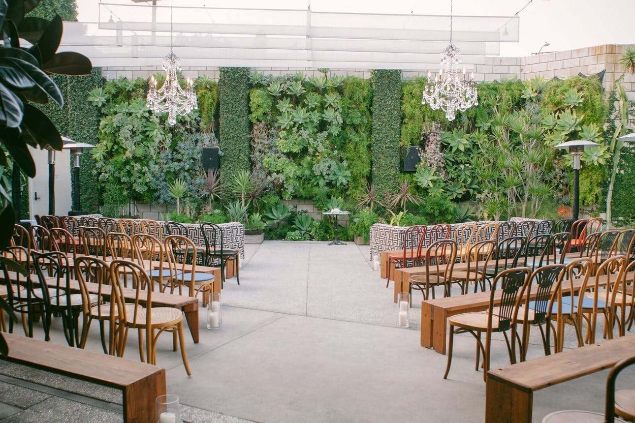 An indoor ceremony with greenery walls and chandeliers at SmogShoppe, Los Angeles