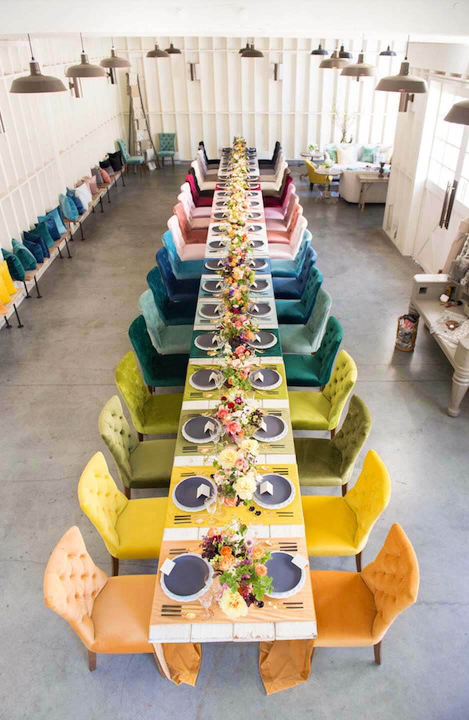 Ассортимент ombre ярких бархатных стульев и сервировки стола с подходящими декоративными подушками.
