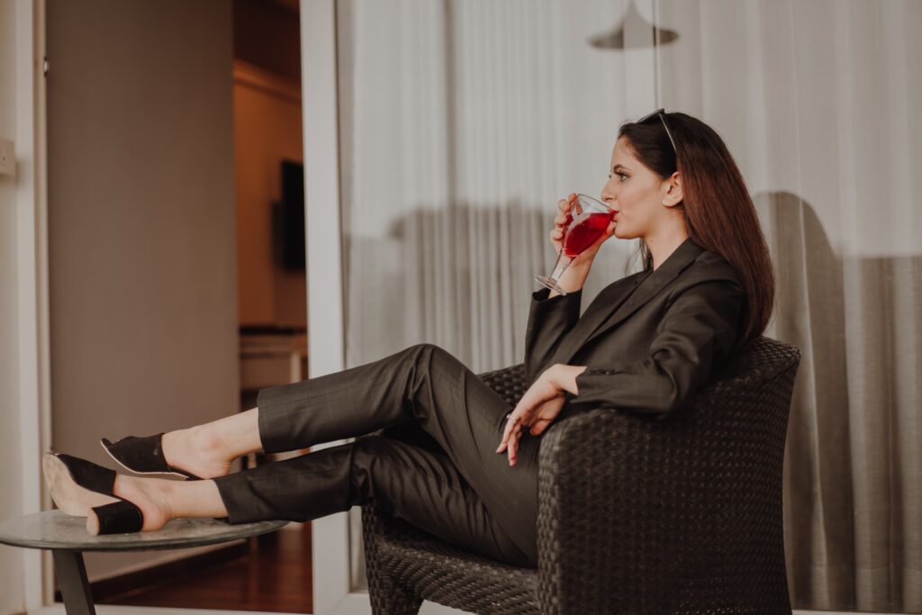 Женщина в женском костюме сидит в кресле и пьет напиток.